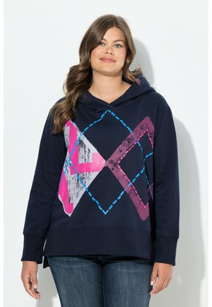 Hoodie bleu marine avec un col cowl arbore un graphique géométrique en rose, bleu et gris, confectionné dans un tissu doux et texturé.