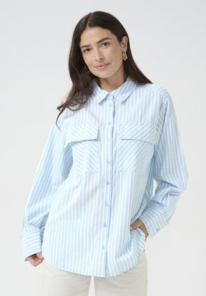 Camicia a righe azzurre e bianche realizzata in tessuto morbido, con chiusura a bottoni, colletto e due tasche sul petto. Maniche lunghe.