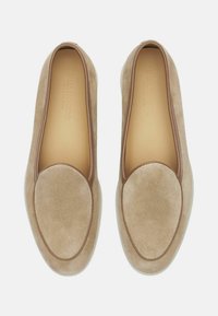 Bež sueded loafersi s glatkim smešnim kožnim obrubom, zaobljenim vrhom i podstavljenim uloškom, koji se odlikuju minimalističkim dizajnom i bešavnom konstrukcijom.