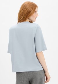 Lichtblauw T-shirt met korte mouwen, in een losse pasvorm, ronde hals en een zachte textuur, gecombineerd met grijze trainingsbroek. Eenvoudig, minimalistisch ontwerp.