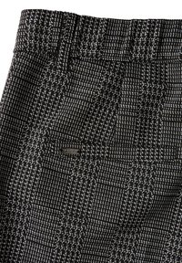 Pantaloni a motivi bianco e nero con un tessuto testurizzato, una ampia cintura elastica e una piccola etichetta di marca sulla tasca laterale.