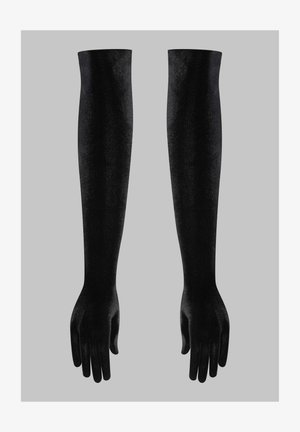 Paire de longs gants en velours noir s'étendant au-delà du coude sur un fond gris uni.