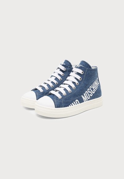 Baskets montantes en denim avec embouts en caoutchouc blanc, lacets blancs, et "MOSCHINO" imprimé en grandes lettres blanches sur le côté.