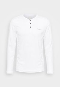Biała koszula z długim rękawem i dekoltem henley, z trzema czarnymi guzikami oraz subtelnym haftem marki po lewej stronie klatki piersiowej. Bawełnowy materiał, gładka tekstura.