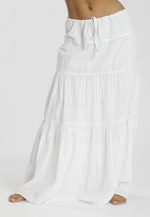 Witte, gelaagde maxi-jurk met oogjespatroon van palmbomen, elastische tailleband en koord, gedragen door een blote voet.