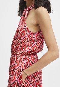 Abito senza maniche con scollo all'americana, realizzato in tessuto a fantasia nei toni del rosa, rosso e marrone; presenta una vita elastica e tasche laterali.