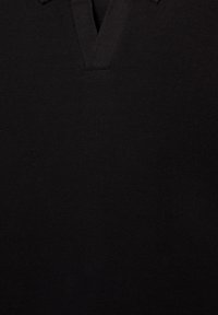 Polo nero con design a V e tessuto a maglia testurizzato. Il colletto è realizzato nello stesso materiale, garantendo un aspetto uniforme.