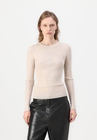 Beige stripete langermet topp med rund hals, tettsittende silhuett og myk tekstur, kombinert med høyt liv sorte skinnbukser.