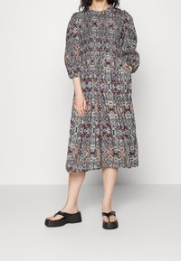 Kukka-ahoitu mekko puffi-hihoilla, smokkibodilla ja polvipituisella hameella mustassa, valkoisessa sekä punaisen ja sinisen sävyissä; sisältää taskut.