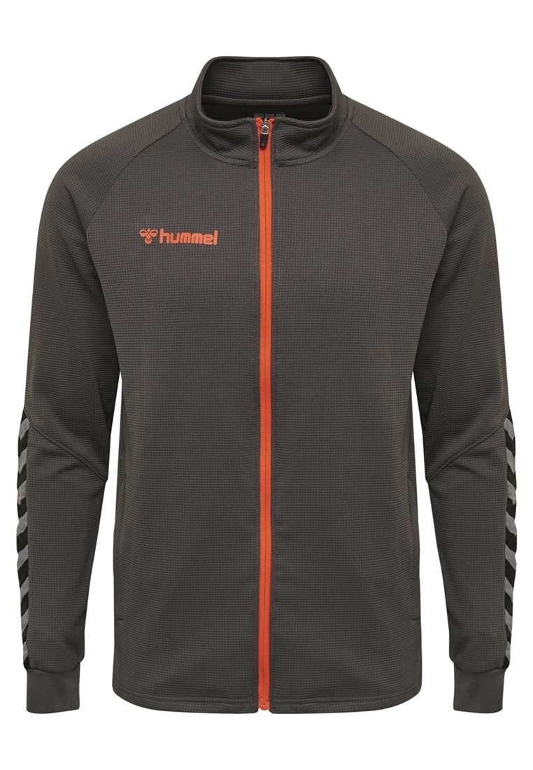 Mörkgrå zip-up jacka i texturerat material, med orange dragkedja och logotyp, samt svarta och vita chevron-accenter på ärmarna.