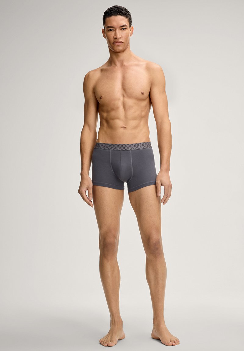 Harmaat bokserialushousut, joissa on kuminauhavyötärö ja teksturoitu kuviointi. Pehmeästä kankaasta valmistetut, istuvaa mallia ja keskireisien pituudelta.