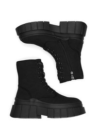 Melni auduma potīšu zābaki ar biezu platformas zolīti, kuriem ir šņores un sānu rāvējslēdzējs, izceļ gluda tekstūra un minimālisma dizains.