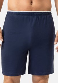 Shorts de sport bleu marine en tissu doux, avec une ceinture élastique et des poches latérales. Design simple, longueur mi-cuisse.