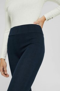 Leggings a scacchi blu navy a vita alta con un tessuto liscio e elasticizzato. L'elastico in vita è largo, mantenendo una silhouette snella.
