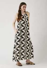 Abito lungo con motivo geometrico bianco e nero, caratterizzato da spalline gialle arruffate e tasche, realizzato in tessuto leggero.