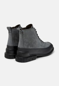 Botas de tobillo de ante gris con punta redonda, cordones en la parte delantera y una suela de goma negra gruesa con ranuras horizontales.
