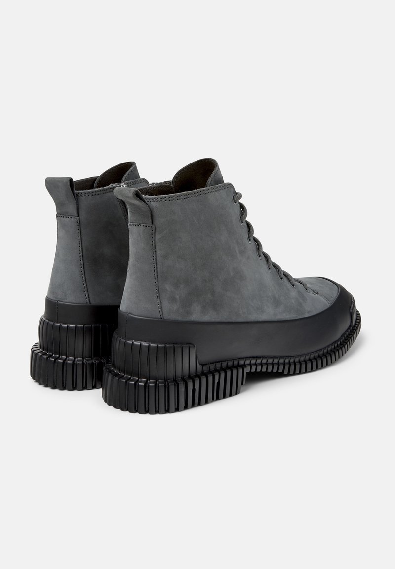 Grey suede ankle boots with a round toe, lace-up front, and a chunky black rubber sole featuring horizontal grooves.