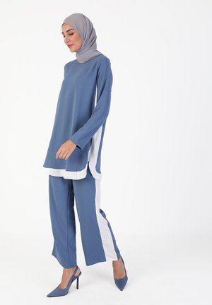 Lightweight blue tunic and pants set with white accents, long sleeves, and a loose fit. Paired with matching blue pointed heels.