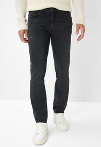 Jeans in denim nero con taglio dritto, design a cinque tasche e leggere sfumature. Abbinati a sneakers bianche e un maglione cremoso strutturato.