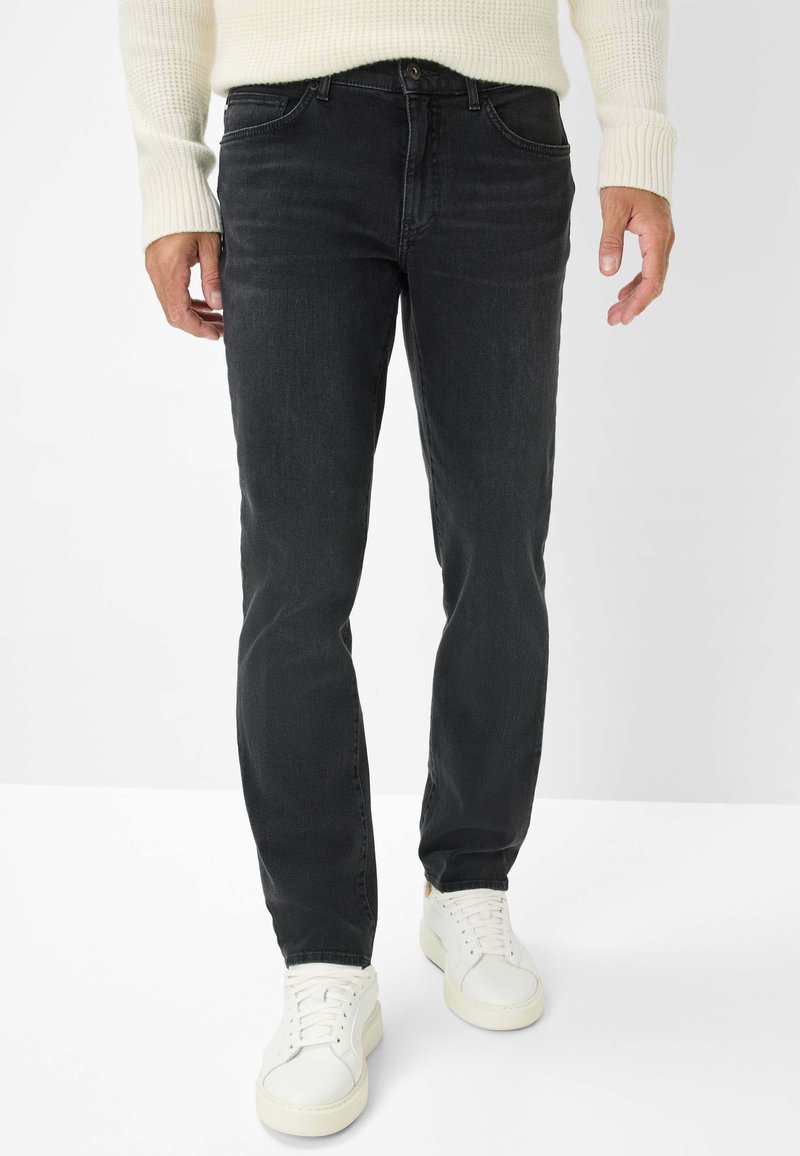 Jeans in denim nero con taglio dritto, design a cinque tasche e leggere sfumature. Abbinati a sneakers bianche e un maglione cremoso strutturato.