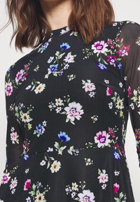 Vestido negro con estampado de flores coloridas en rosa, azul y blanco. Hecho de una tela ligera, con un corsé ajustado y falda acampanada.