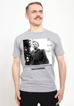 Szara bawełniana koszulka z czarno-białą grafiką zamaskowanej postaci, z napisem "Każdy ma prawo do jednego dobrego strachu."