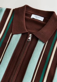 Pehmest ja tekstuurse kangaga kampsun, millel on pruunide, roheliste ja akvamariinsete triipudega lukk-särk. Omadusteks on soonikuga krae ja hõbedase tõmblukuga detail. Moodne lõige.