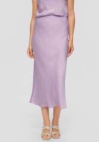 Lila satijnen rok met een gladde textuur, voorzien van een middellange snit en een lichte flare aan de onderkant. Gecombineerd met naakte sandalen met banden.