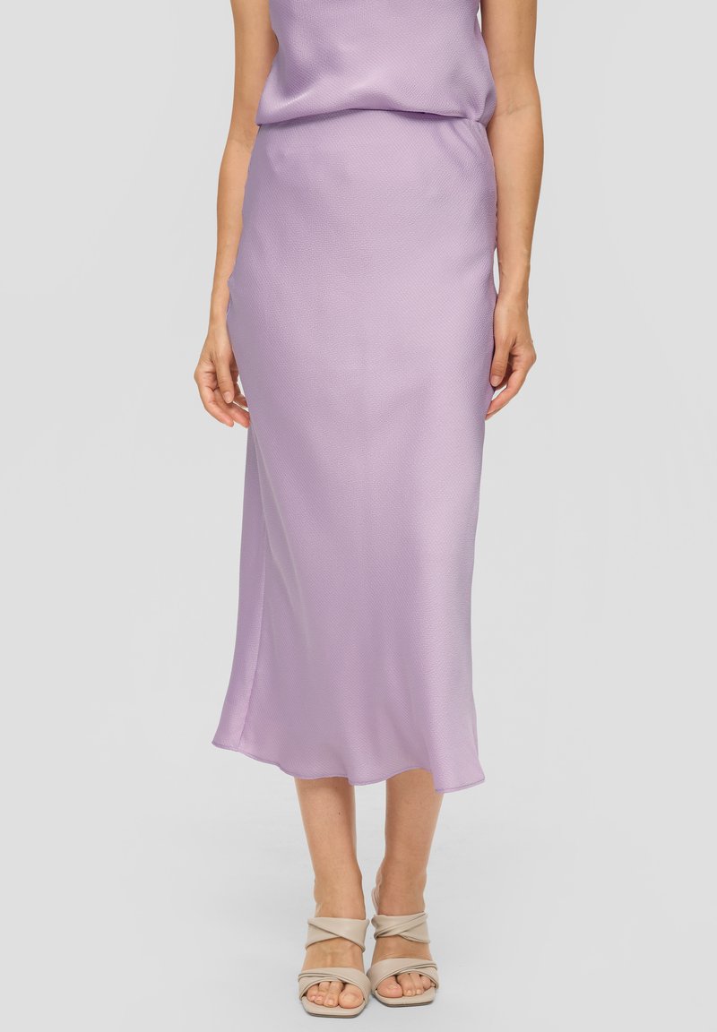 Lila satijnen rok met een gladde textuur, voorzien van een middellange snit en een lichte flare aan de onderkant. Gecombineerd met naakte sandalen met banden.