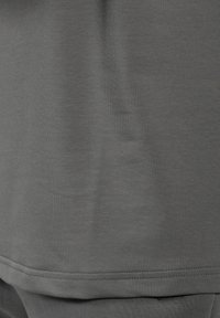 Grå bomulds t-shirt med en glat tekstur. Har en rund halsudskæring og korte ærmer, samt en lige kant. Enkel, ensfarvet design.