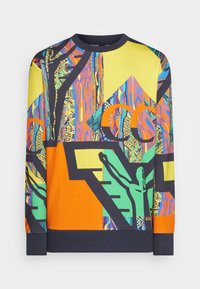 Sweatshirt coloré présentant un mélange de motifs géométriques et abstraits en jaune, orange, vert et bleu sur un fond noir.