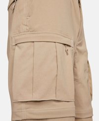 Beige cargoshorts i lättviktsmaterial har flera fickor, synliga sömmar och en avslappnad passform med veck och snörningsdetaljer.