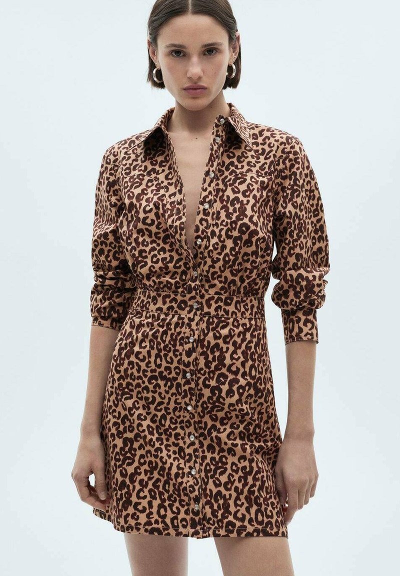 Abito a camicia con stampa leopardata realizzato in un tessuto morbido. Presenta una vita aderente, maniche arrotolate e un colletto. I toni terrosi dominano il design.