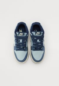 Nike sneakers med en blå og marineblå overdel, canvasmateriale, rund tå, stofsnørebånd og en beige gummisål. Logo på tungen.