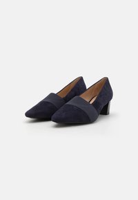 Décolleté in camoscio blu navy con punta affusolata, dotate di una larga fascia in tessuto sulla tomaia e un tacco quadrato. Progettate per un fit strutturato e stabilità.
