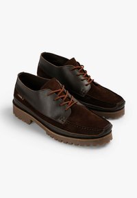 Zapatos de cuero marrón oscuro con parte superior de ante y cuero liso, cordones marrón anaranjado y suela de goma rugosa y texturizada.
