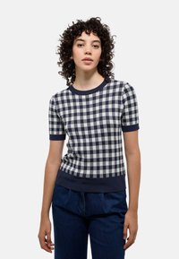 Sweater à manches courtes à carreaux en marine et beige. Comprend un col rond et une bordure côtelée aux manches et à l'ourlet. La texture est en tricot.