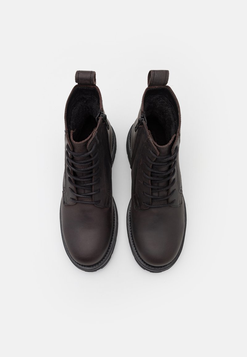 Para ciemno-brązowych skórzanych butów za kostkę na sznurówki z bocznymi zamkami i pętelkami do łapania, przedstawione z góry na białym tle.