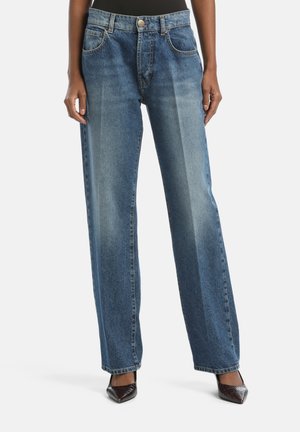 Weite blaue Jeans aus ausgewaschenem Denim, mit fünf Taschen, einem Knopfverschluss und einer glatten Textur. Begleitet von schwarzen spitzen Schuhen.