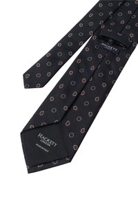 Svart silkesbindel med ett upprepande mönster av små paisleymönster i rött och vitt. Etiketten säger "HACKETT LONDON" och "MADE IN ITALY."