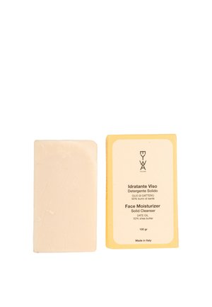 Crema idratante solida per il viso in una barra rettangolare beige, accanto a una scatola gialla con testo nero che evidenzia gli ingredienti chiave come olio di datteri e burro di karité.