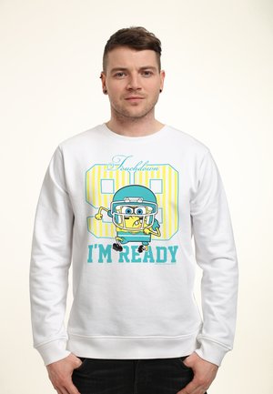 Man draagt een witte hoodie met een cartoonfiguur in voetbaluitrusting en de tekst "Touchdown 98 I'm Ready" aan de voorkant.