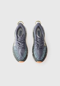 Des chaussures de course violettes et vertes avec une tige texturée, un logo proéminent, une semelle rembourrée et des accents orange ; elles disposent de languettes sur le talon.