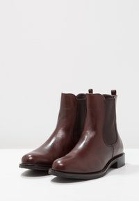 Braune Lederchelsea-Boots mit glatter Textur, elastischen seitlichen Einsätzen und Zuglaschen. Runde Zehenpartie und niedriger Blockabsatz.
