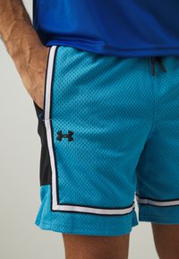 Pantalones cortos deportivos de malla azul con acentos negros, ribete blanco y bolsillos laterales. Presenta un pequeño logo negro en el lado izquierdo.