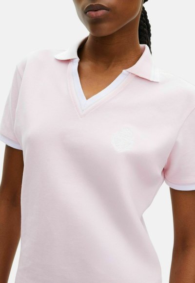 Lichtroze polo shirt met V-hals, witte kraagrand en geborduurd logo op de linkerborst. Gemaakt van textuurstof.