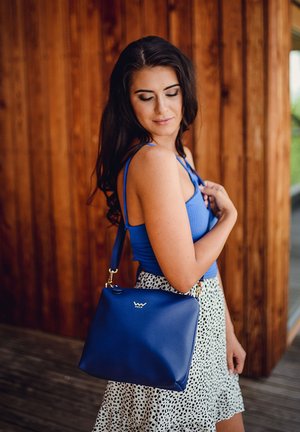 Royal blue leather handbag with a smooth texture, gold hardware, and a subtle logo. The bag features a single shoulder strap.