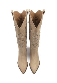 Beige suede knee-high boots with pointed toe, decorative silver studs, and scalloped top edges. Designed with pull tabs on the sides.