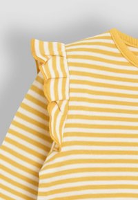 Gelb-weiß gestreiftes Shirt mit gerafftem Schultervolant, runder Ausschnitt und weichem Baumwollmaterial.