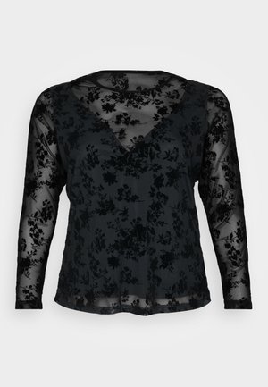 Blouse noire à manches longues présentant un motif floral sur un tissu transparent, décolleté en V et coupe décontractée. Texture douce avec design superposé.